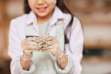 无法辨认的女孩在车间制作手工陶器时塑造粘土的特图片