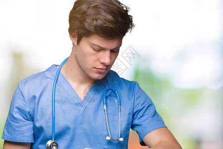 身穿医疗制服的年轻医生在孤立的背景下检查手表的时间图片