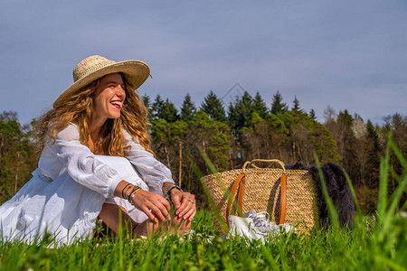 年轻女士戴着太阳帽子坐在草地上对图片