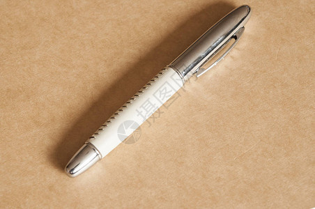 钢笔位于棕色纸背景上图片