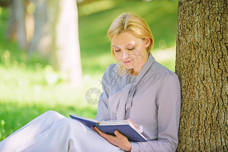 畅销书排行榜每个女孩都应该读的书放松休闲爱好概念最好的女自助书籍女孩集中坐在公园瘦树干上看书阅读鼓背景图片