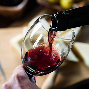 男人往玻璃杯里倒红酒的特写镜头背景图片