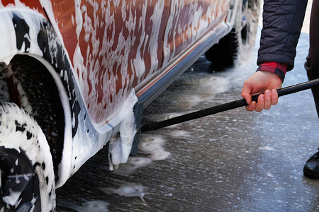 男人用刷子洗他的橙色汽车图片