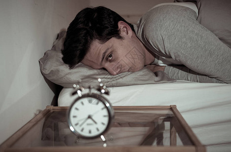 失眠和绝望的年轻白人男子晚上醒来无法入睡背景图片