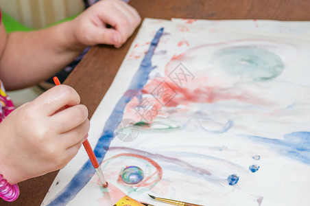 一个小女孩在幼稚园用油漆和刷子画出一张明图片