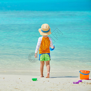三岁的小孩在沙滩上玩海滩玩具在马尔代夫度暑假的图片