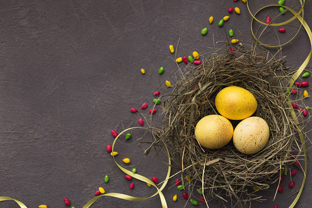 在灰石背景的灰石本底筑巢配有多彩甜食的黄东蛋将贺卡混为春季假日顶视图图片