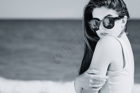 一个漂亮的女孩的肖像长头发在时光太阳镜上棕榈反射在海滩上摆布图片