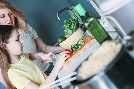 Tween女孩和她妈在家厨房做菜沙拉图片