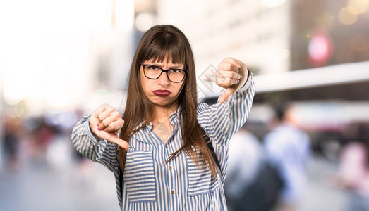 戴眼镜的女人在户外大拇指朝下图片