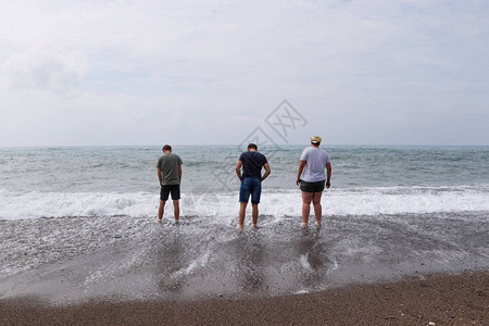 三个最好的朋友去海边年轻人去试水温男人们站在海边图片