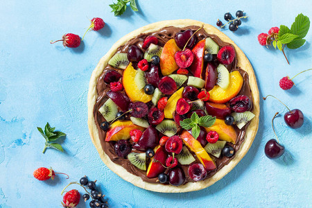 美味自制的夏季水果莓披萨饼和蓝色石头桌上的巧克力面糊图片