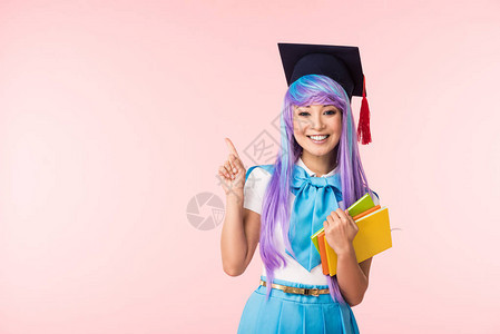 戴着学术帽的微笑亚洲动漫女孩拿着书本图片