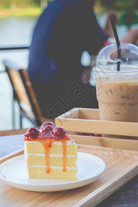海绵蛋糕配樱桃糖浆樱桃蛋糕的和平服务与冰咖啡舒适的户外咖啡馆图片