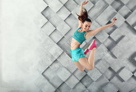 灰色墙壁上的运动型跳跃女人图片