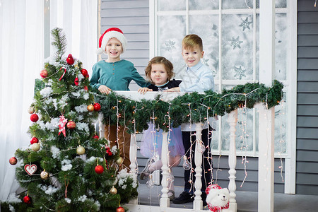 小孩子和圣诞节三个小孩在室内圣诞树附近玩得很开心图片