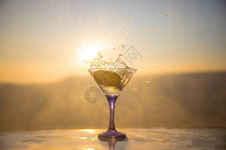 马丁尼鸡尾酒杯喷洒在浓雾的日落背景上图片