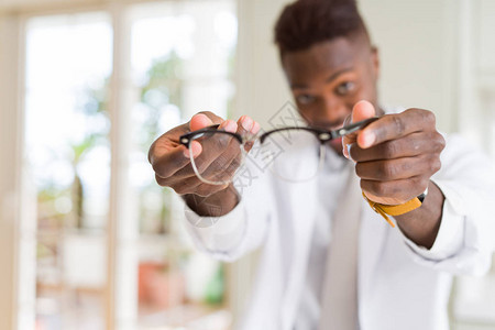 非洲裔美国眼镜男在光学店里拿着眼镜并向顾客展示眼镜图片