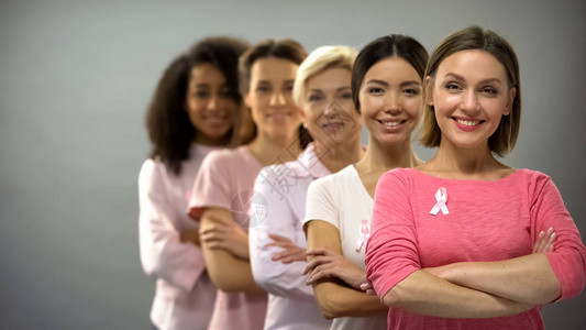 穿着粉色衬衫和乳癌丝带的妇女微笑排图片