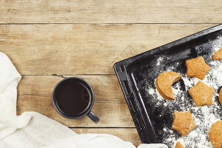 烤盘上的手工饼干和木制背景上的热茶或咖啡杯图片