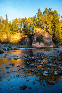 美丽的金色日出在森林河上海岸上有沙石悬崖图片