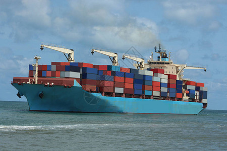 一艘载运集装箱的货船在海洋背景图片