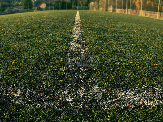 人造绿色足球场上的白色条纹黄叶落在绿色足球草地图片