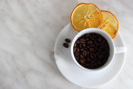 一个杯子和茶碟里装满了烤咖啡豆两片干橙子和一对咖啡豆图片