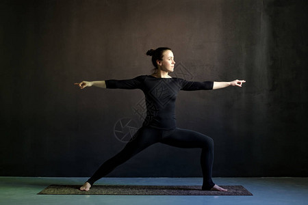 练瑜伽勇士姿势的年轻女子维拉巴德拉萨纳图片
