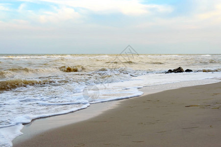 岸边的海浪海浪紧贴在阳光下的沙滩上图片