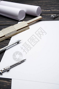 黑色的木桌上是绘图工具用铅笔尺子和圆规绘制图纸放置在桌子上的指南针和建图片