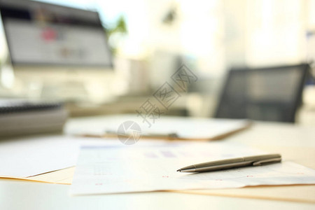 银笔躺在空工作台特写的财务统计文件上图片