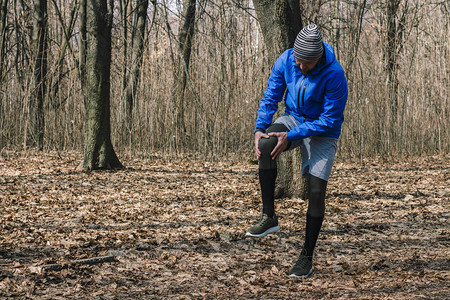 一名穿着训练服的男子在户外锻炼时慢跑时膝盖受伤运动损伤跑步技术错误跑步肌腱炎图片