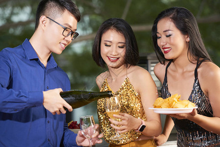 盛装香槟杯的亚洲帅哥在派对上给背景图片
