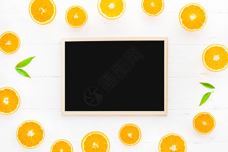 创造斯堪的纳维亚风格的平面在白色木桌背景上用黑板框架模型放置新鲜橙色水果片的顶部视图博客或食谱书的最小夏季背景图片