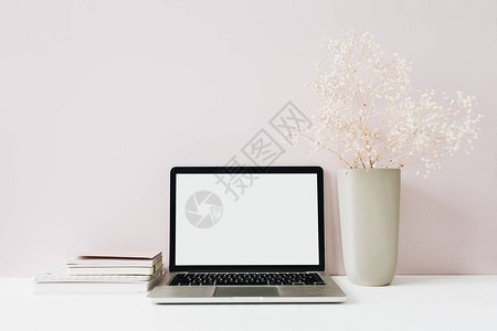 粉红色背景上的笔记本电脑和鲜花束前视图最小的现代家庭办公桌工作区空白屏幕模拟英雄标题博客社交媒体网站模板女图片