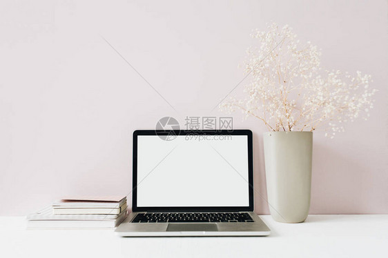 粉红色背景上的笔记本电脑和鲜花束前视图最小的现代家庭办公桌工作区空白屏幕模拟英雄标题博客社交媒体网站模板女图片