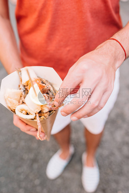 意大利街头食品在男手中烤海鲜鱼虾图片