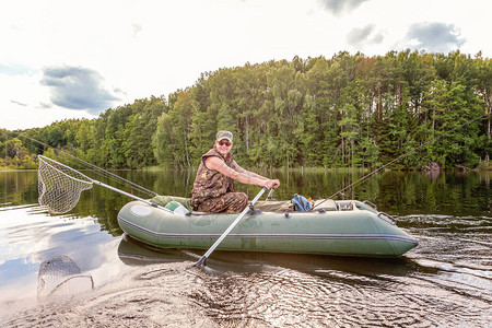 有钓鱼竿的渔夫在美丽的自然和湖泊或河流的背景下在橡皮艇上钓鱼露营旅游放松旅行积极生活图片