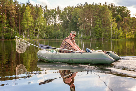 有钓鱼竿的渔夫在美丽的自然和湖泊或河流的背景下在橡皮艇上钓鱼露营旅游放松旅行积极生活图片