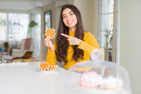 年轻女人吃甜美的华夫饼糕非常快乐地用图片