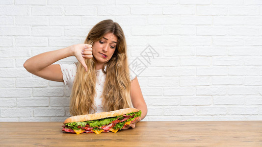 年轻金发女金发美女拿着一个大三明治图片