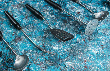 蓝色混凝土背景上的复古金属烹饪工具图片
