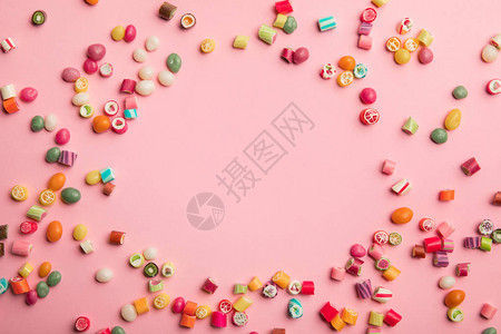 粉红色背景上分布的多色糖果视图上图片