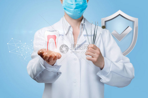 医生在防护罩上拿着假牙模型和一套牙科工具的特写镜头图片