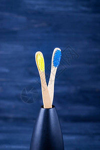 深蓝色背景的明黄色和蓝竹牙刷生态友好概念最小化版面背景图片