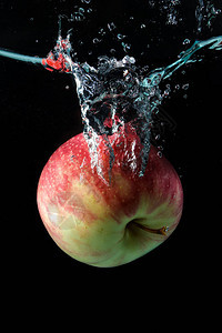黑色背景下水中的苹果飞溅图片
