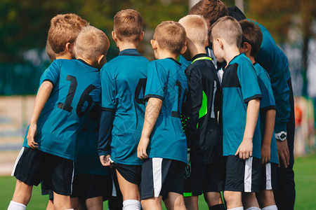 TeamHuddle中的足球男孩与足球教练挤在一起的孩子们图片