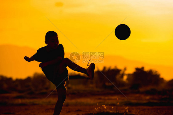 一群孩子在日落下在社区农村地区踢足球锻炼的剪影图片