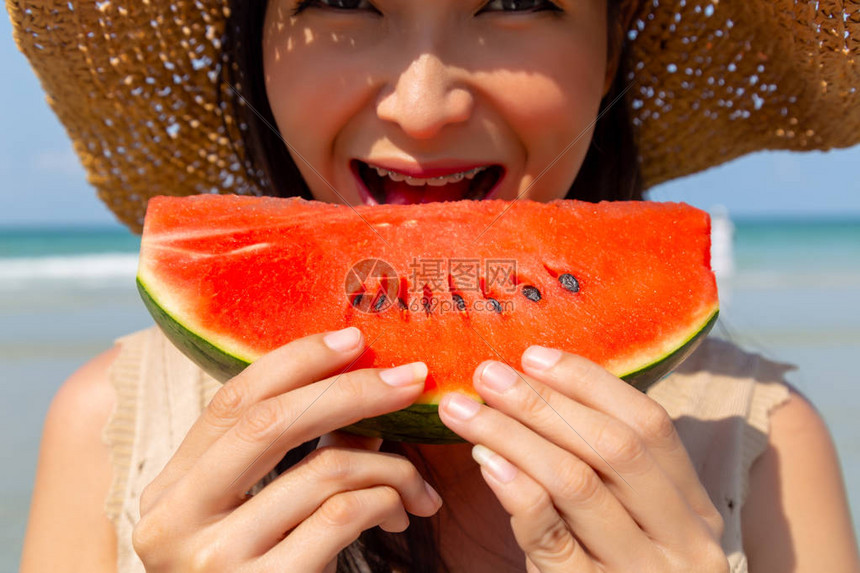 迷人美丽的年轻女子在海滩上吃西瓜来降温和解渴它看起来多汁又甜迷人的美丽亚洲女孩用图片